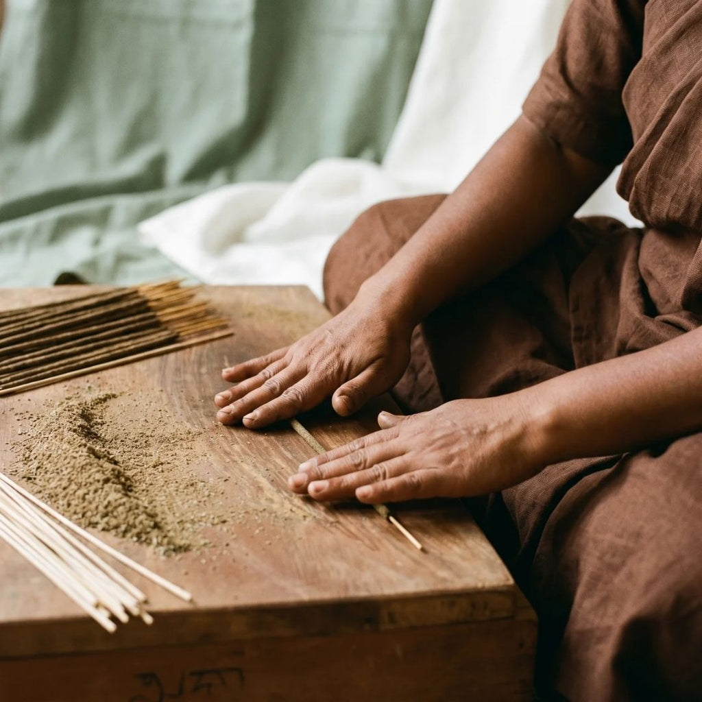 una donna nell'azione di rollare un incenso naturale a mano fiore d'oriente